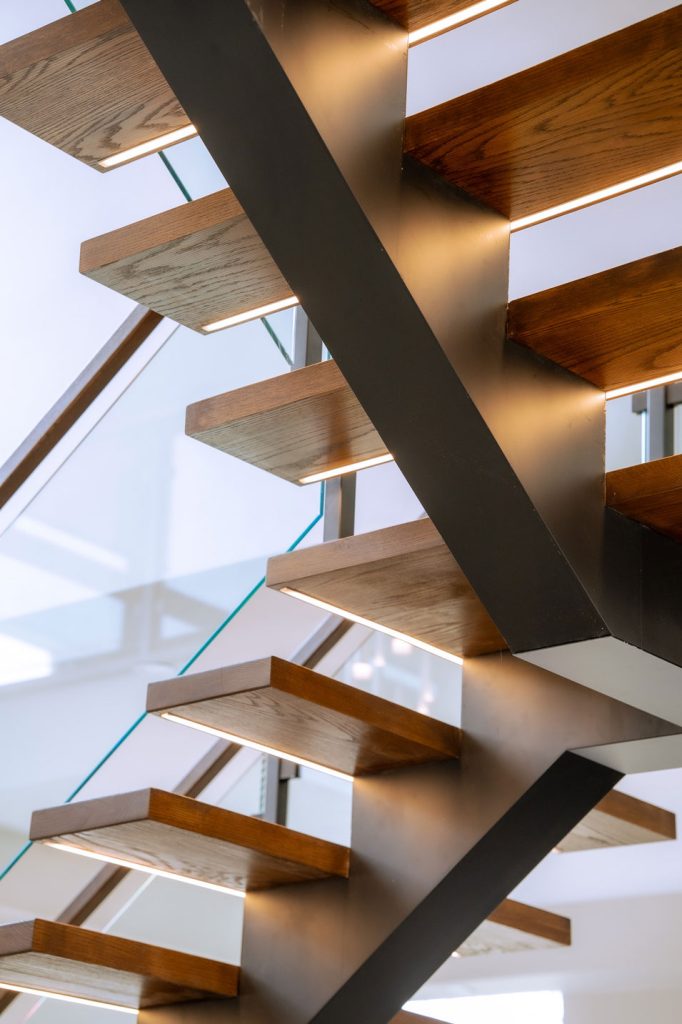 Modern mono-stringer staircase with wooden steps and sleek railing design by Deslo Stairs & Railings